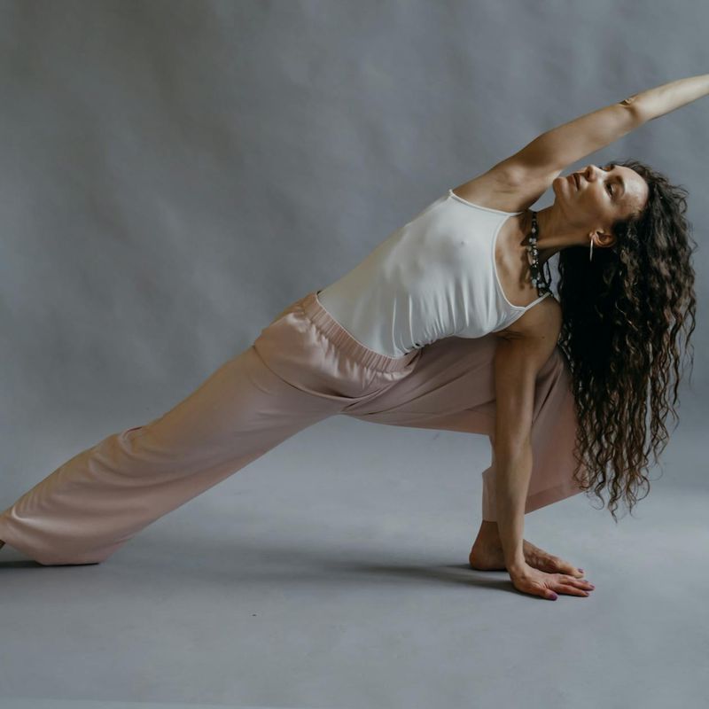 A person in a flowing yoga pose in a sunlit studio.