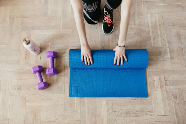 Close-up of a yoga mat and a water bottle on a wooden floor.